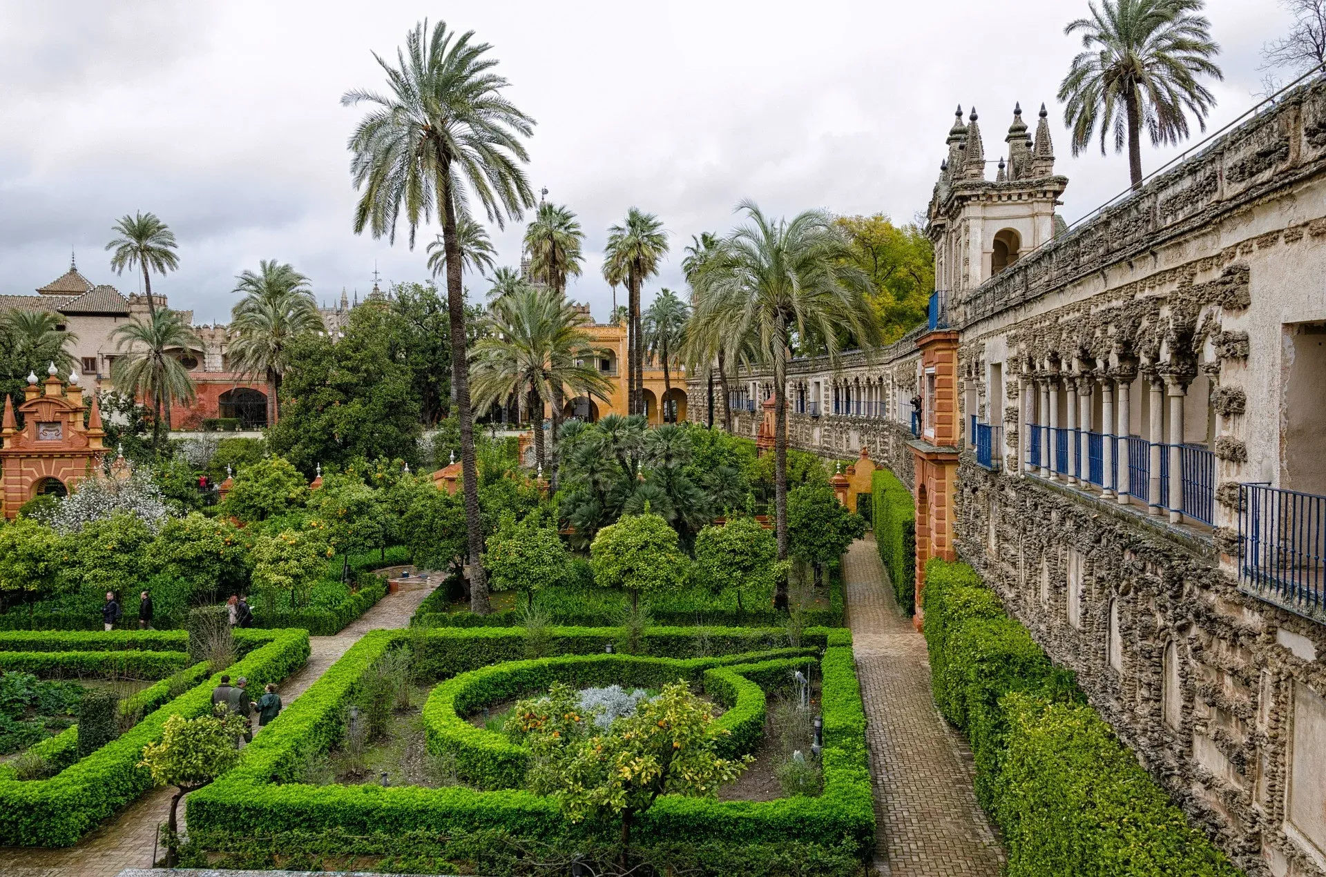 Formal axis in the Royal Alcázar gardens with palms and manicured hedges